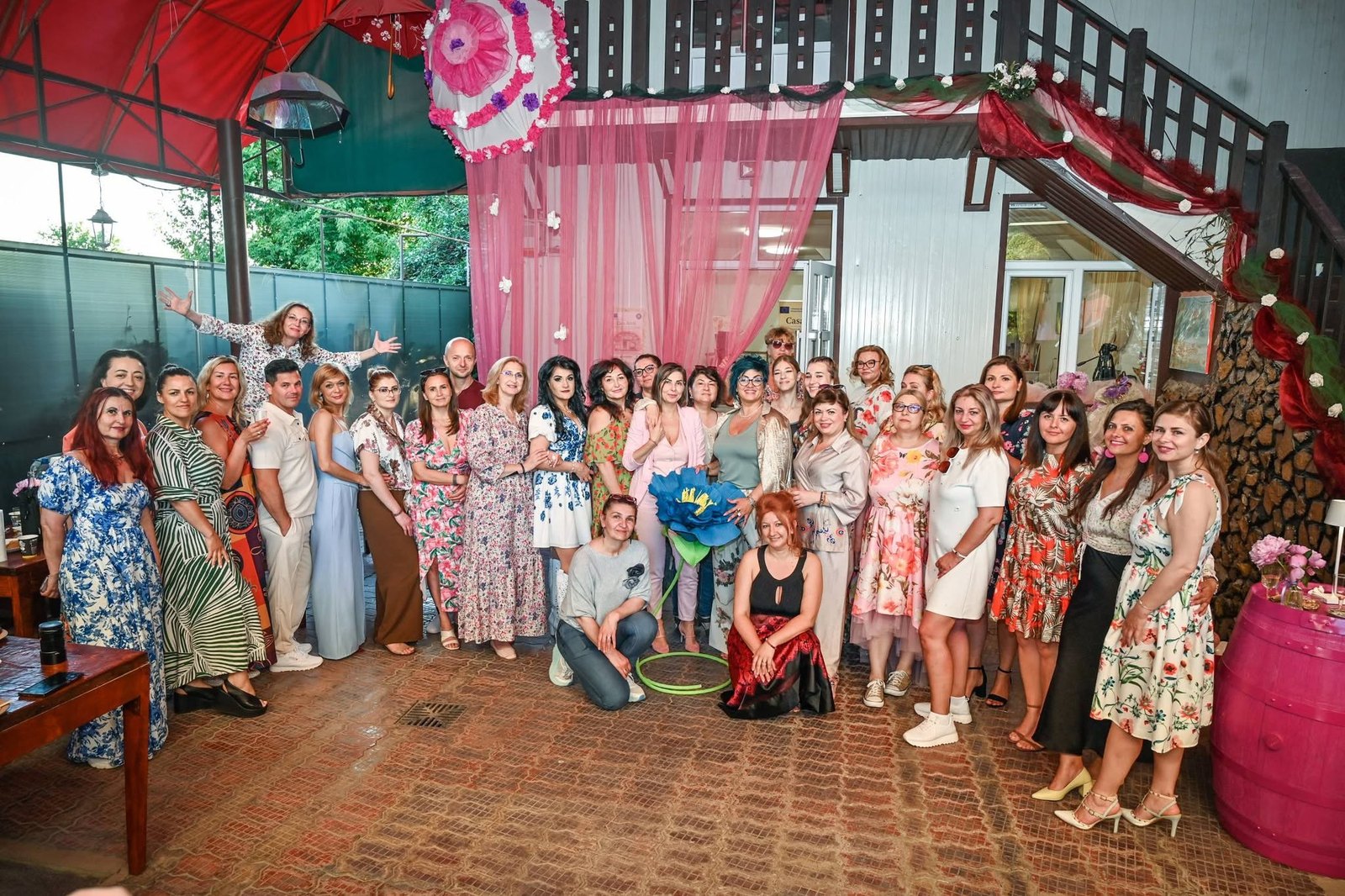 Participanții la un eveniment în curtea Casei ArtIS, sub umbrele colorate